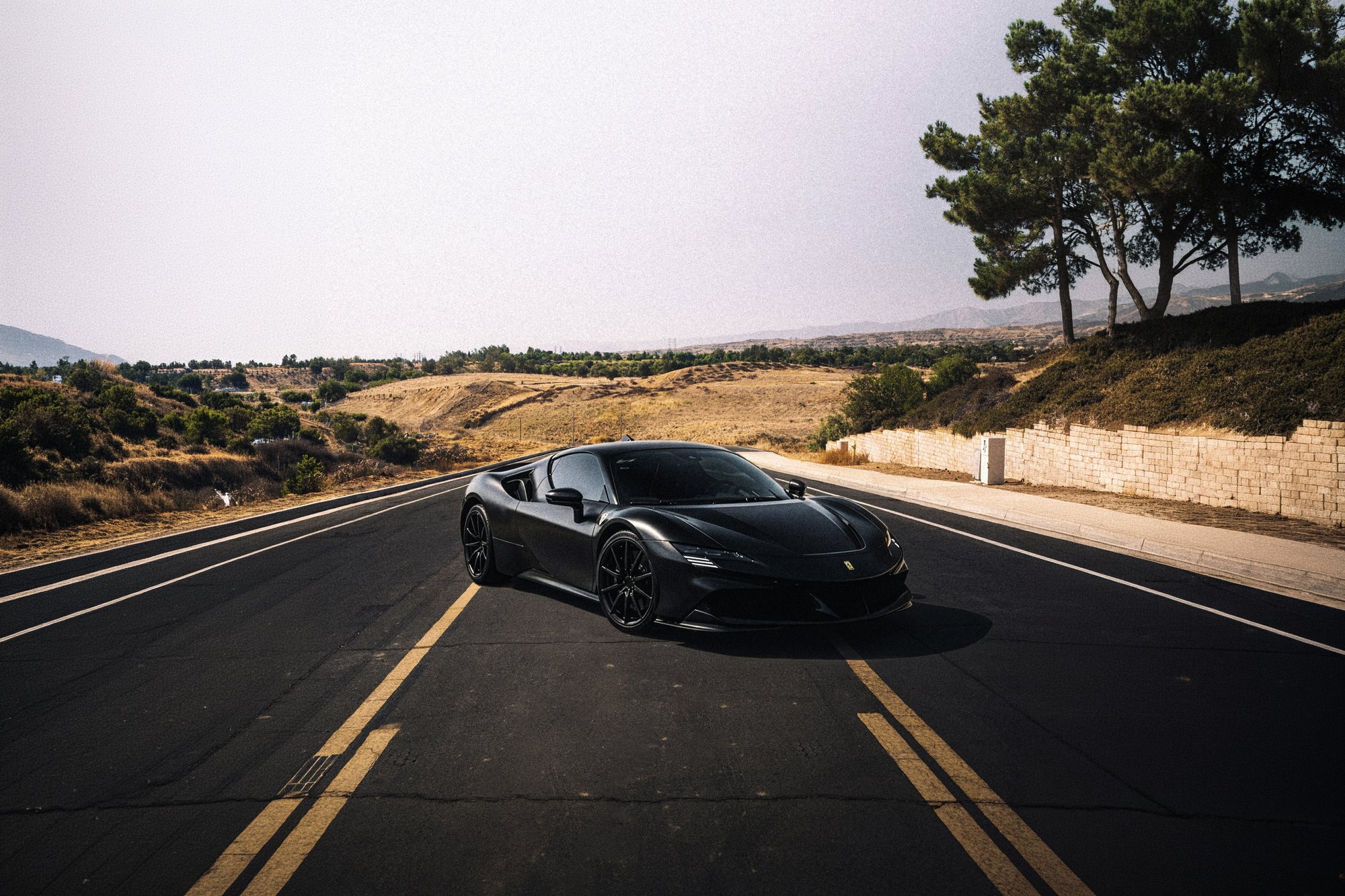 Matte black 2021 Ferrari SF90 with tinted windows on a Beaumont road