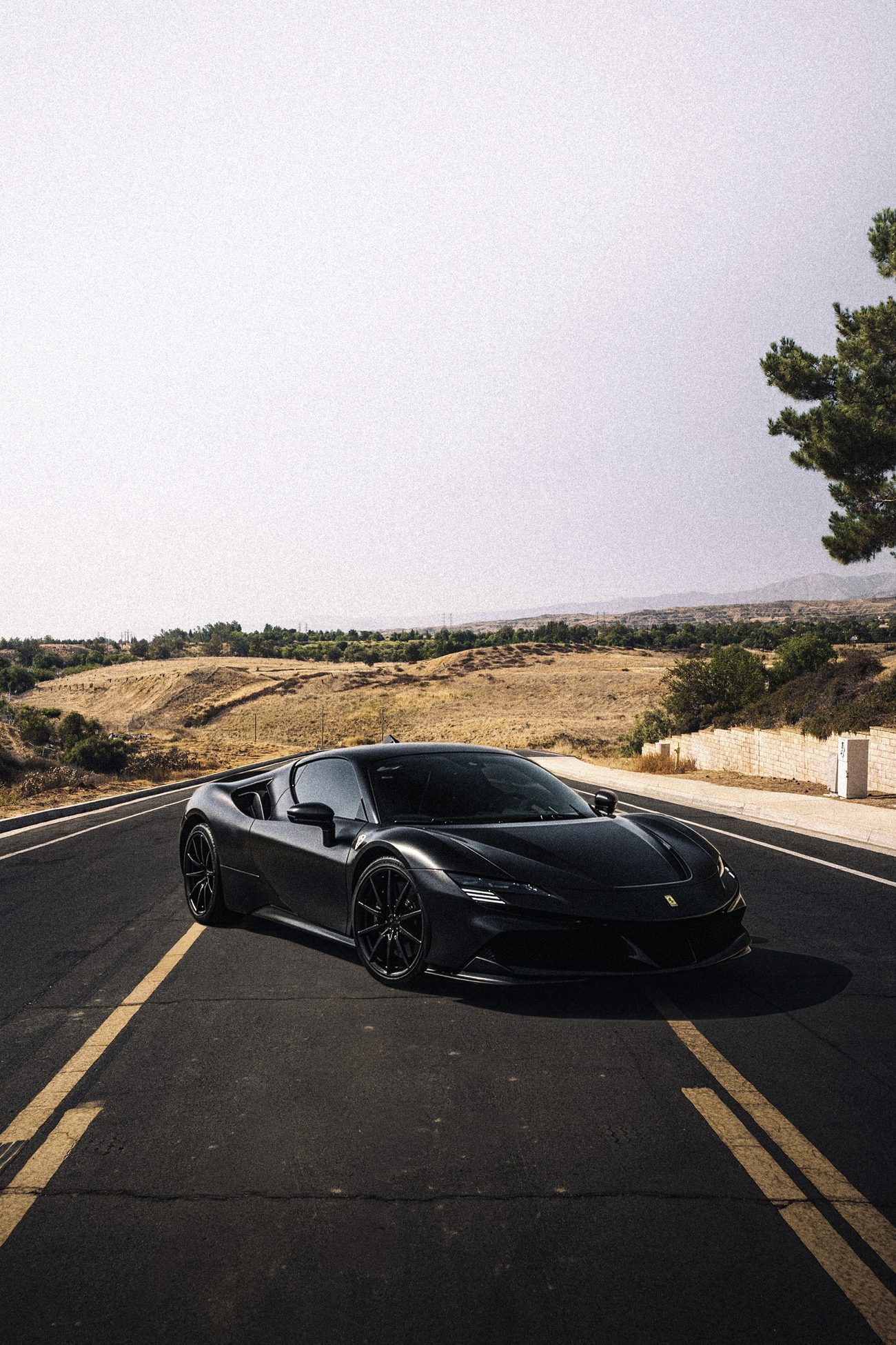 Matte black 2021 Ferrari SF90 with tinted windows on a Beaumont road